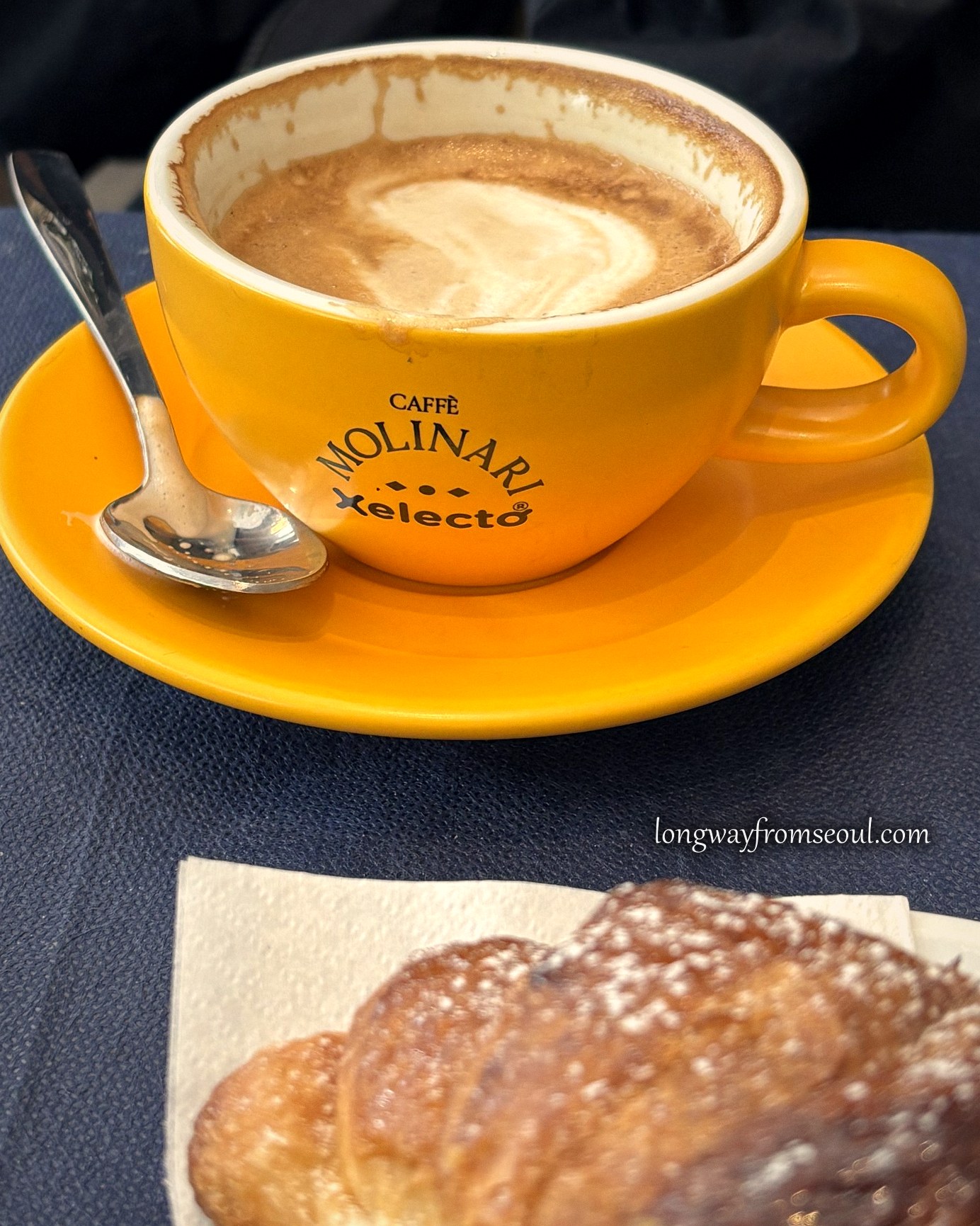 Caffè latte and a cornetto on a café table in Prati, Rome