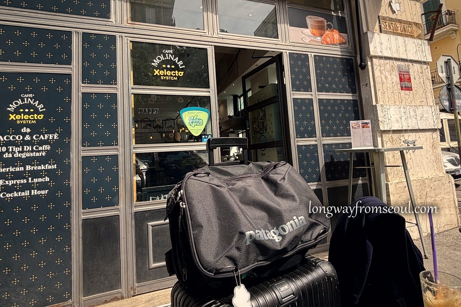 Suitcases and a backpack beside a café window in Prati, Rome