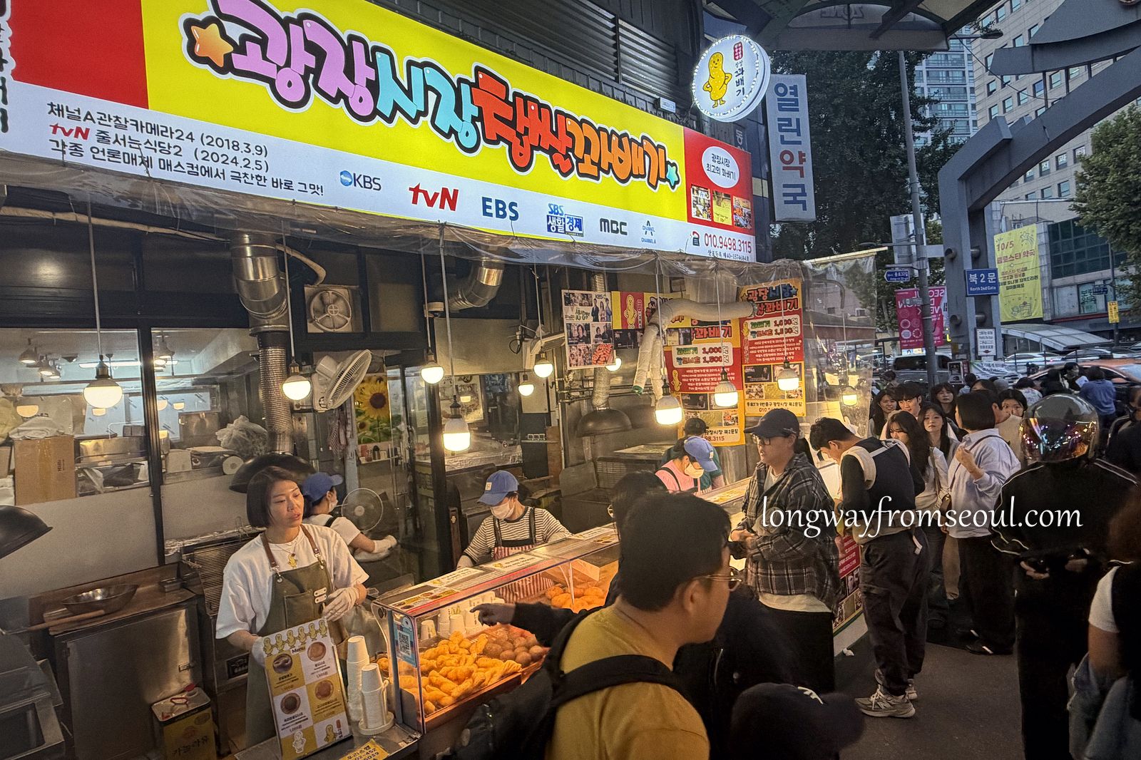 A food stall in the alleys of Gwangjang Market with fried snacks under heat lamps