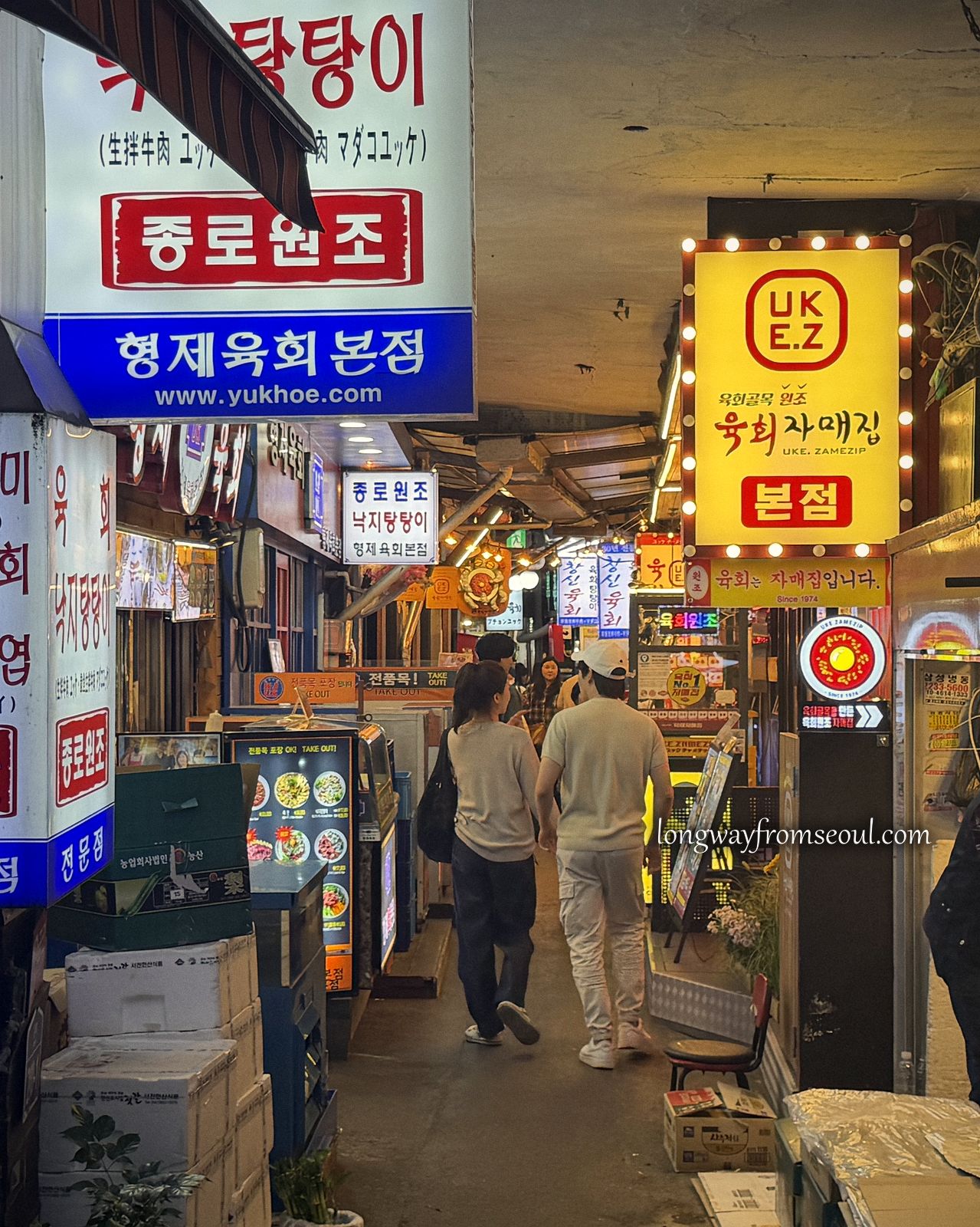 A narrow alley of neon restaurant signs beside Gwangjang Market in Jongno, Seoul