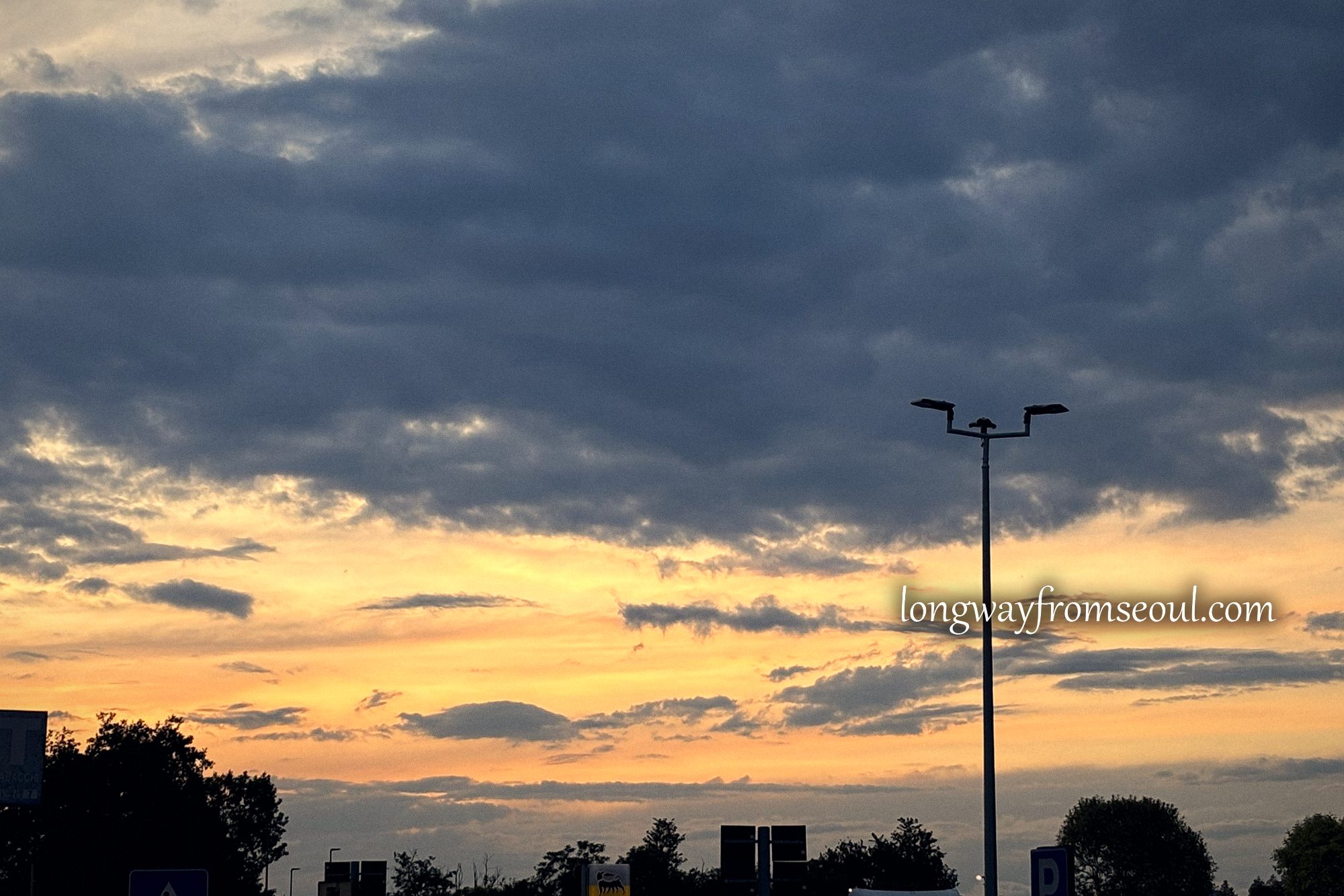 Orange and grey sunset clouds over an Italian motorway service area