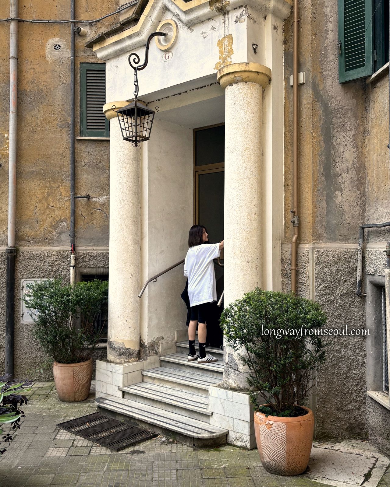 A woman stepping into the doorway of an apartment building in Prati, Rome