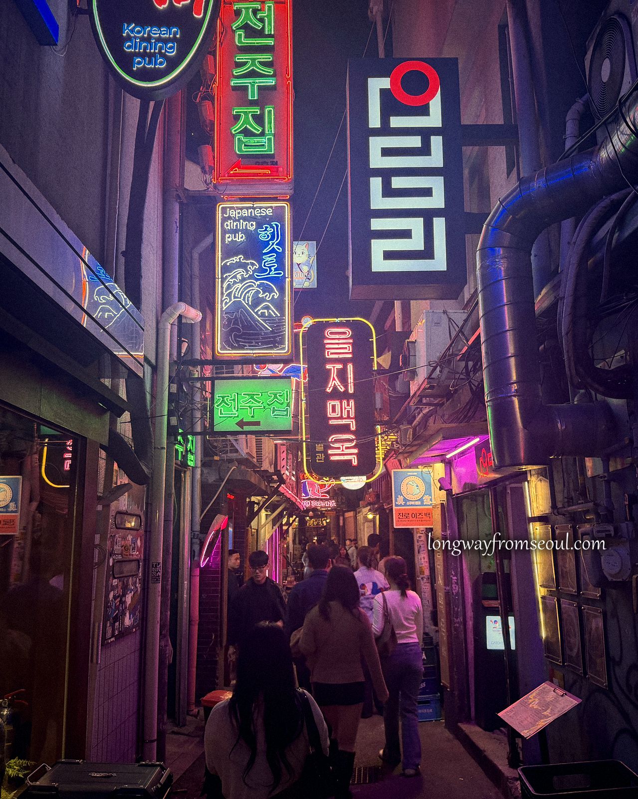 A narrow Euljiro alley at night stacked with glowing neon signs in magenta and green