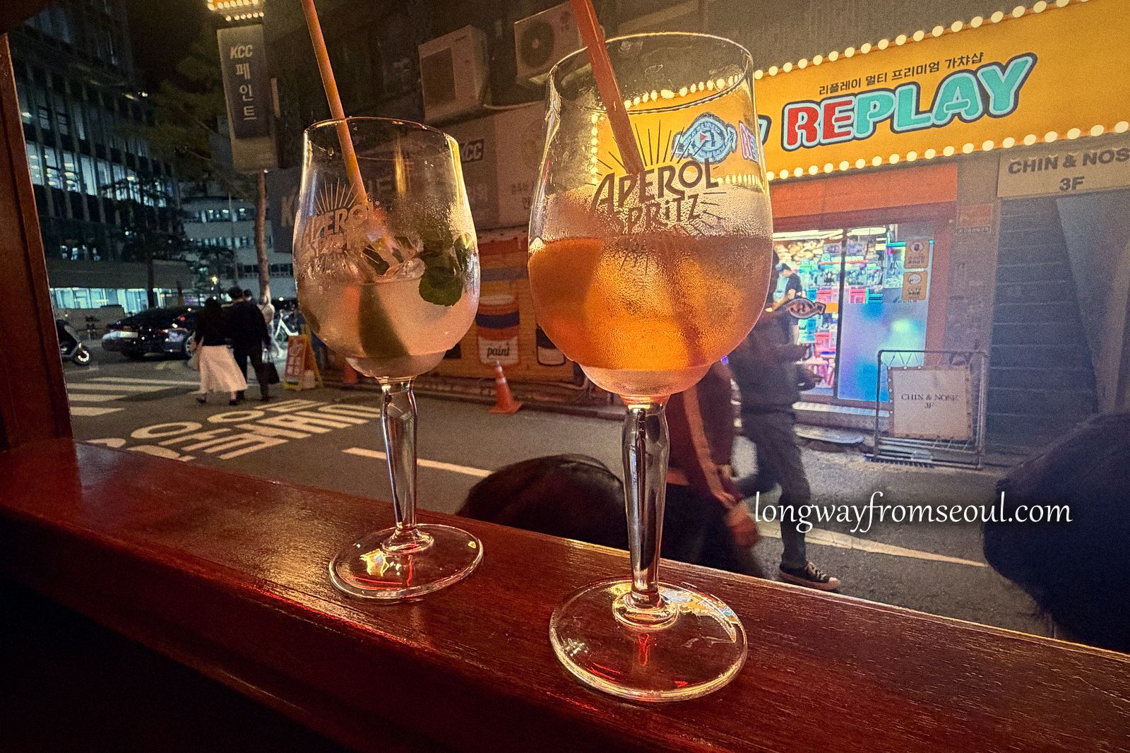 Two cocktails on a window ledge overlooking a neon-lit street in Euljiro, Seoul