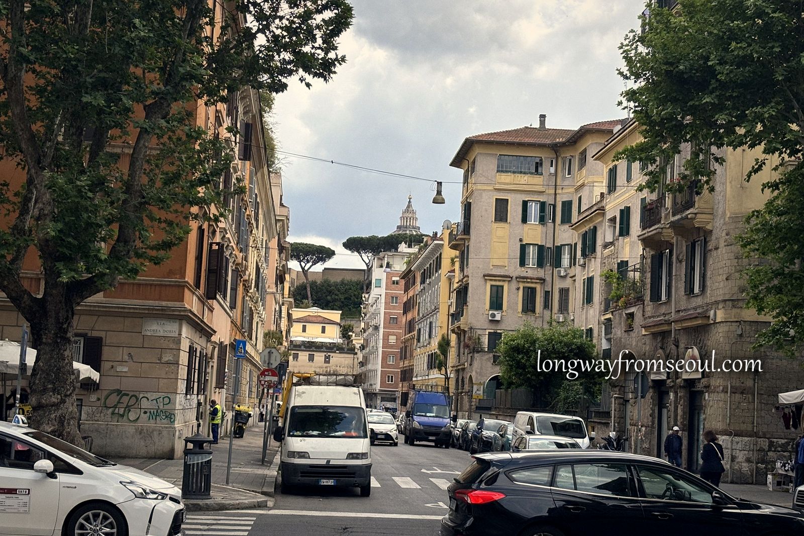 A residential street in the Trionfale district of Rome with parked cars and umbrella pines