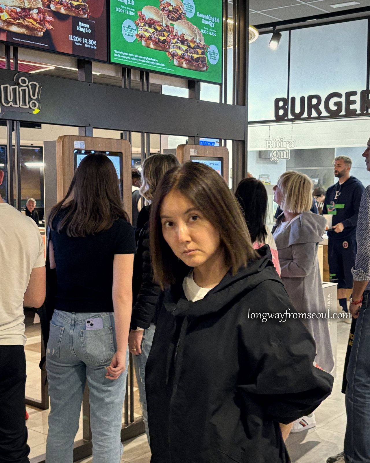 A woman standing inside an Italian motorway service station at night